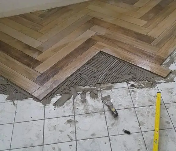 Instalare parchet în spic în hol cu praf de construcție vizibil