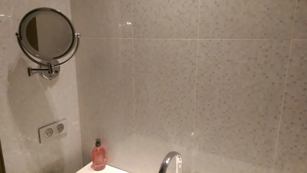 Detaliu de baie cu oglindă rotundă și perete placat