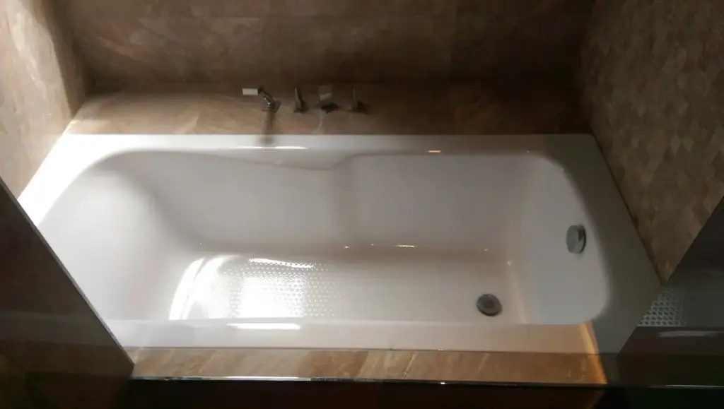 Cadă baie albă nouă în peisaj de șantier, pereți necompletați în spate, praf
