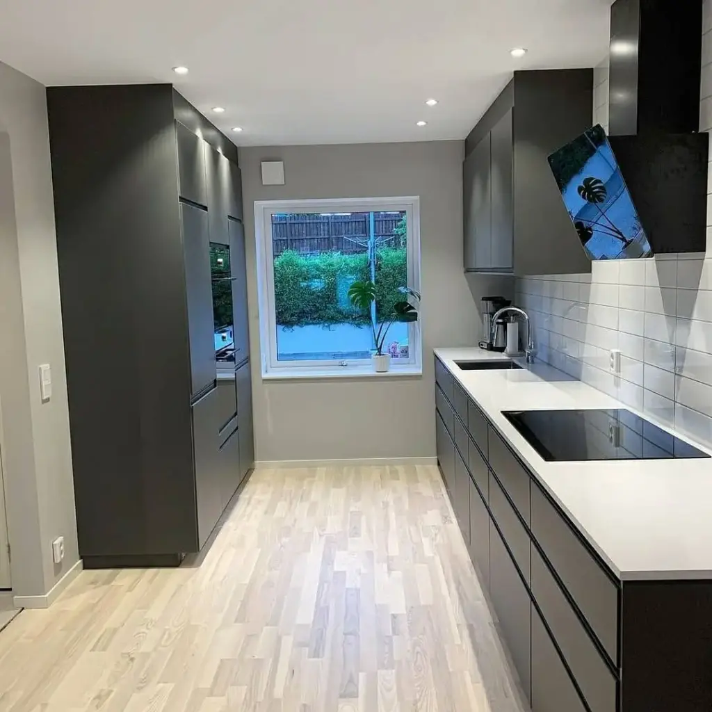 Bucătărie finalizată, mobilier gri inchis și alb, blat alb, gresie albă pe pereți