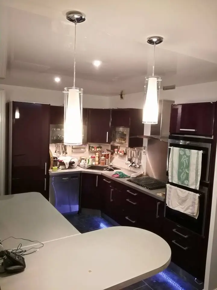 Bucătărie cu mobilă neagră, blat marmură alb, rafturi negre built-în, gresie albă, hota