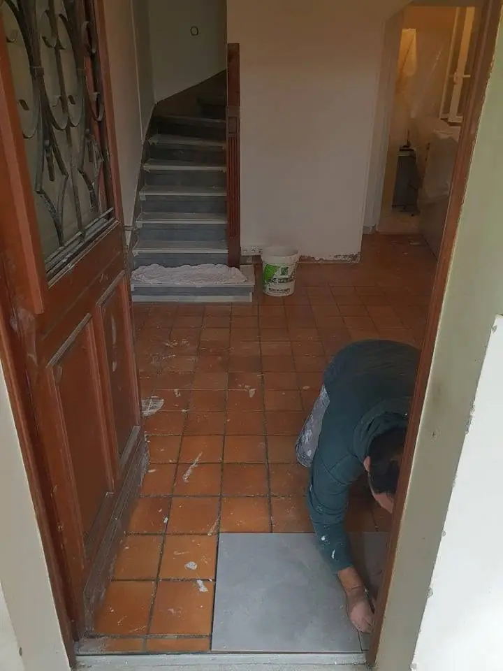 Hol/intrare cu scări, muncitor vizibil, scări cu trepte gri, pereți partiati albi și