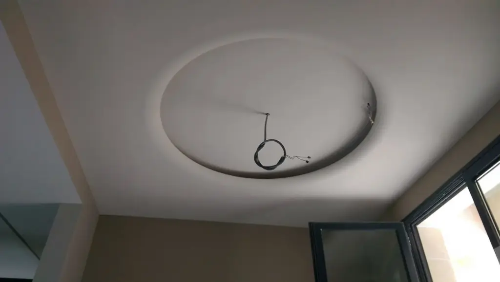 Tavan cu corp de iluminat circular în lucru, cabluri electrice expuse în gol