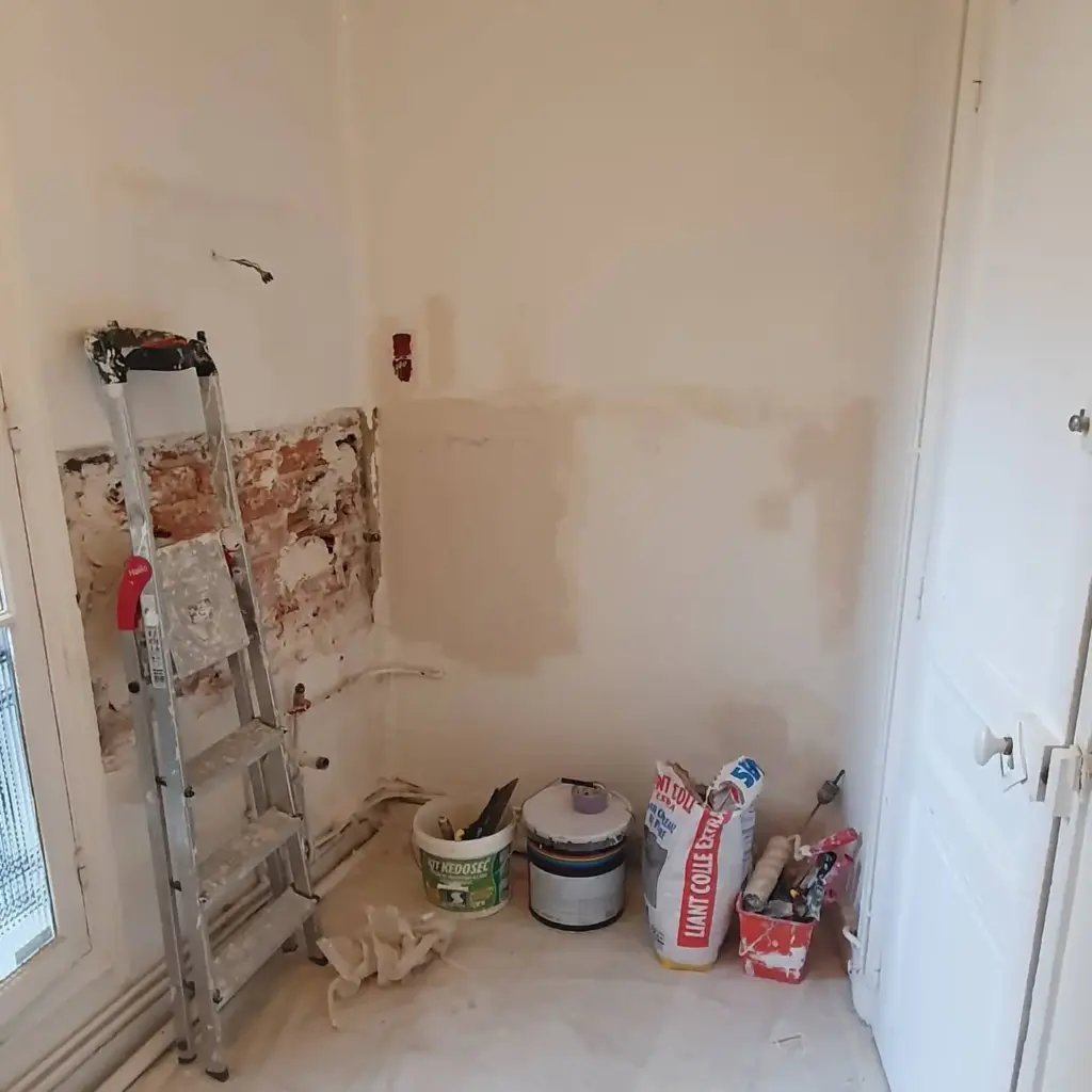 Cameră în stadiu de renovare cu pereți pregătiți, scară, materiale și scule de